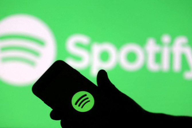 Sebuah smartphone terlihat di depan layar proyeksi logo Spotify pada ilustrasi gambar yang diambil 1 April 2018 ini.