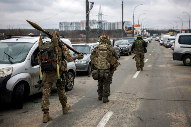 Prajurit Ukraina membawa granat berpeluncur roket dan senapan sniper saat mereka berjalan menuju kota Irpin, barat laut Kyiv, pada 13 Maret 2022