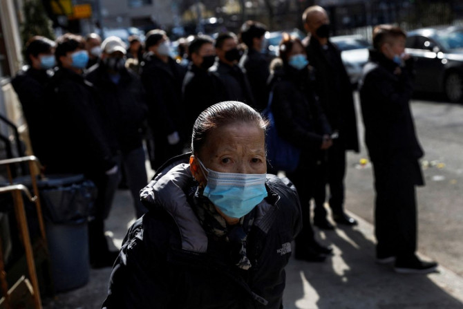 Seorang wanita yang mengenakan masker pelindung, di tengah pandemi penyakit virus corona (COVID-19), berjalan selama prosesi pemakaman di bagian Chinatown di wilayah Manhattan di New York City, AS, 10 Februari 2022.