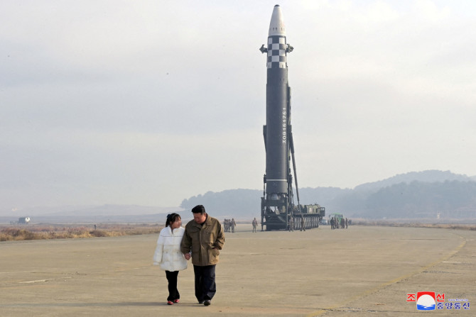 Pemimpin Korea Utara Kim Jong Un, bersama dengan putrinya, berjalan menjauh dari ICBM dalam foto tak bertanggal yang dirilis oleh KCNA