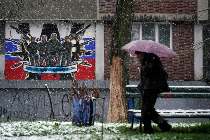 Seorang pejalan kaki melewati mural yang dirusak ke Grup Wagner tentara bayaran Rusia di Beograd pada 20 Januari 2023