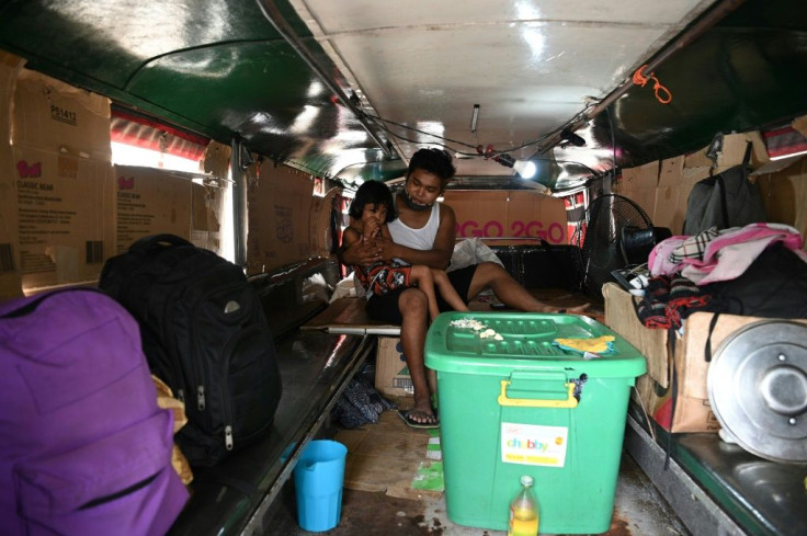 Pengemudi Jeepney Daniel Flores merawat salah satu anaknya di dalam kendaraan mereka, yang telah menjadi tempat penampungan sementara