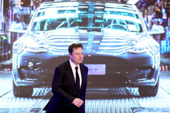 CEO Tesla Inc Elon Musk berjalan di samping layar yang menampilkan gambar mobil Tesla Model 3 saat upacara pembukaan program Model Y buatan China Tesla di Shanghai