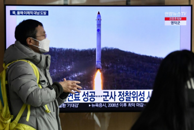 Seorang pria berjalan melewati layar televisi yang menayangkan siaran berita dengan rekaman file uji coba rudal Korea Utara, di sebuah stasiun kereta api di Seoul pada 31 Desember 2022 setelah Korea Utara menembakkan tiga rudal balistik jarak pendek menur