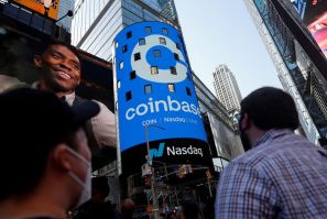 Orang-orang menonton saat logo Coinbase Global Inc, pertukaran cryptocurrency AS terbesar, ditampilkan di jumbotron Nasdaq MarketSite di Times Square di New York