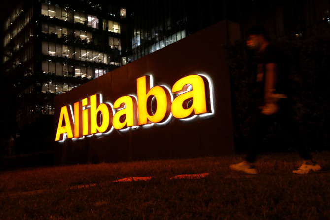 Seorang pria berjalan melewati logo Grup Alibaba di gedung kantornya di Beijing