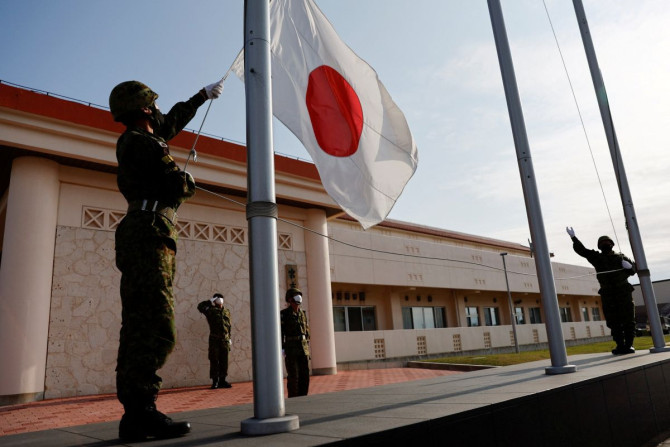 Anggota Pasukan Bela Diri Darat Jepang (JGSDF) menurunkan bendera nasional Jepang pada sore hari, di kamp JGSDF Miyako di Pulau Miyako, prefektur Okinawa, Jepang 20 April 2022.