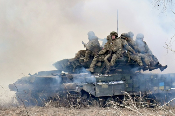 Tentara Ukraina duduk di atas tank tempur menyebarkan tabir asap saat mereka mengikuti latihan militer