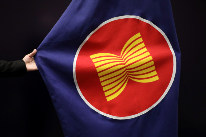 Seorang pekerja menyesuaikan bendera ASEAN di sebuah balai pertemuan di Kuala Lumpur