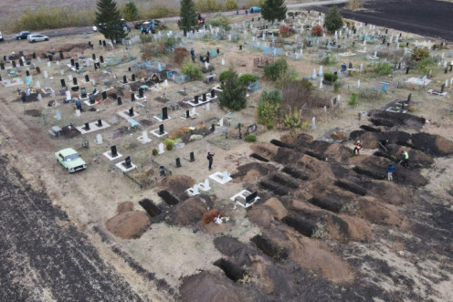 Sebuah foto udara yang diambil dengan drone menunjukkan para pekerja menggali kuburan untuk para korban serangan udara di desa Groza di wilayah Kharkiv, Ukraina.