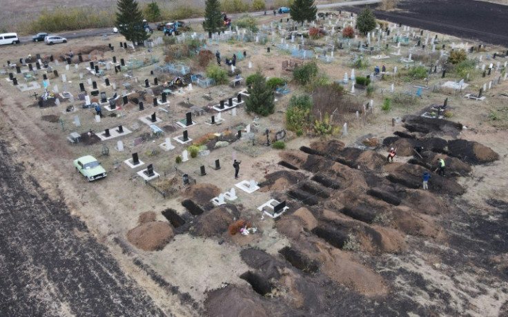 Sebuah foto udara yang diambil dengan drone menunjukkan para pekerja menggali kuburan untuk para korban serangan udara di desa Groza di wilayah Kharkiv, Ukraina.